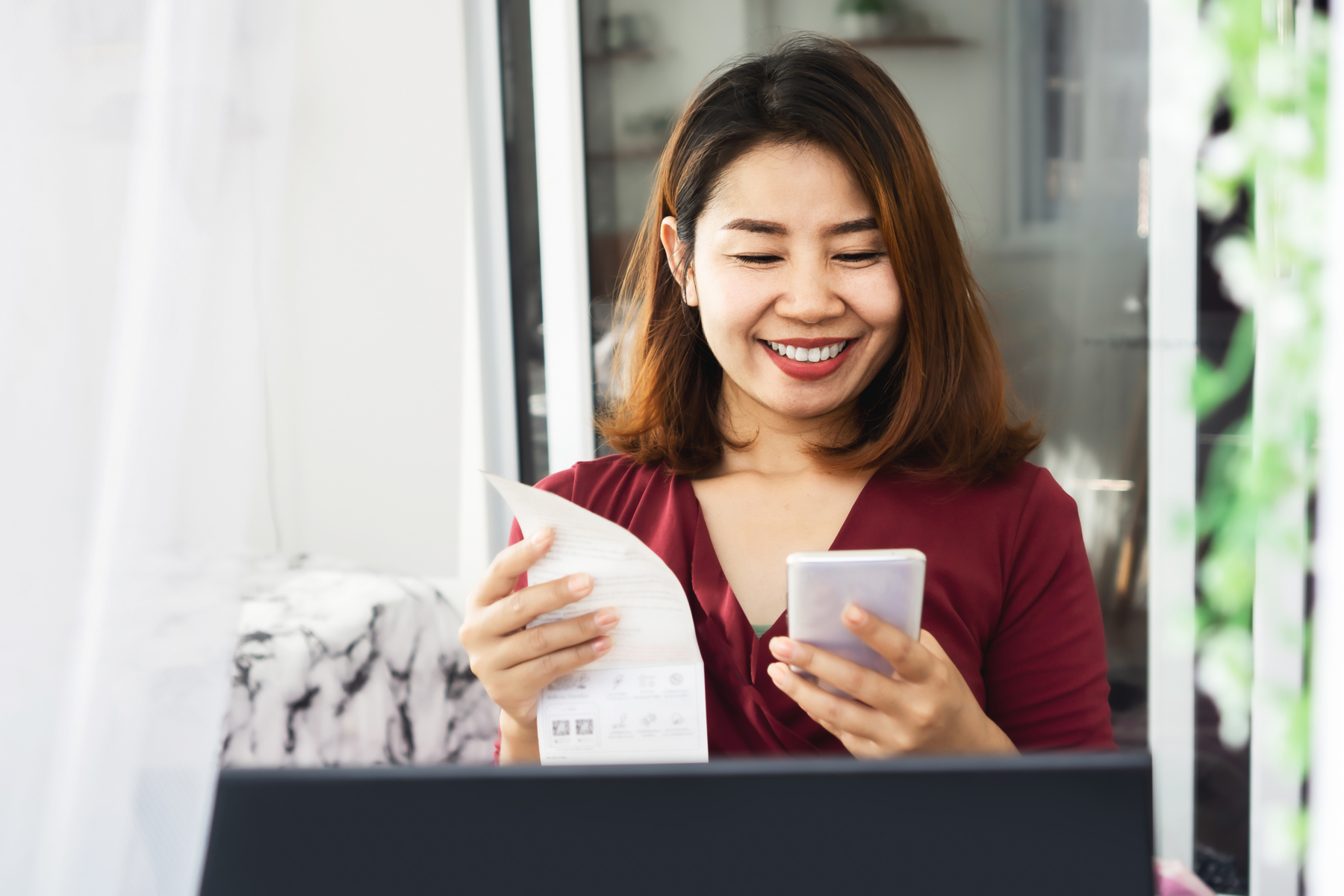 happy Asian woman paying electricity bill hand holding smart phone